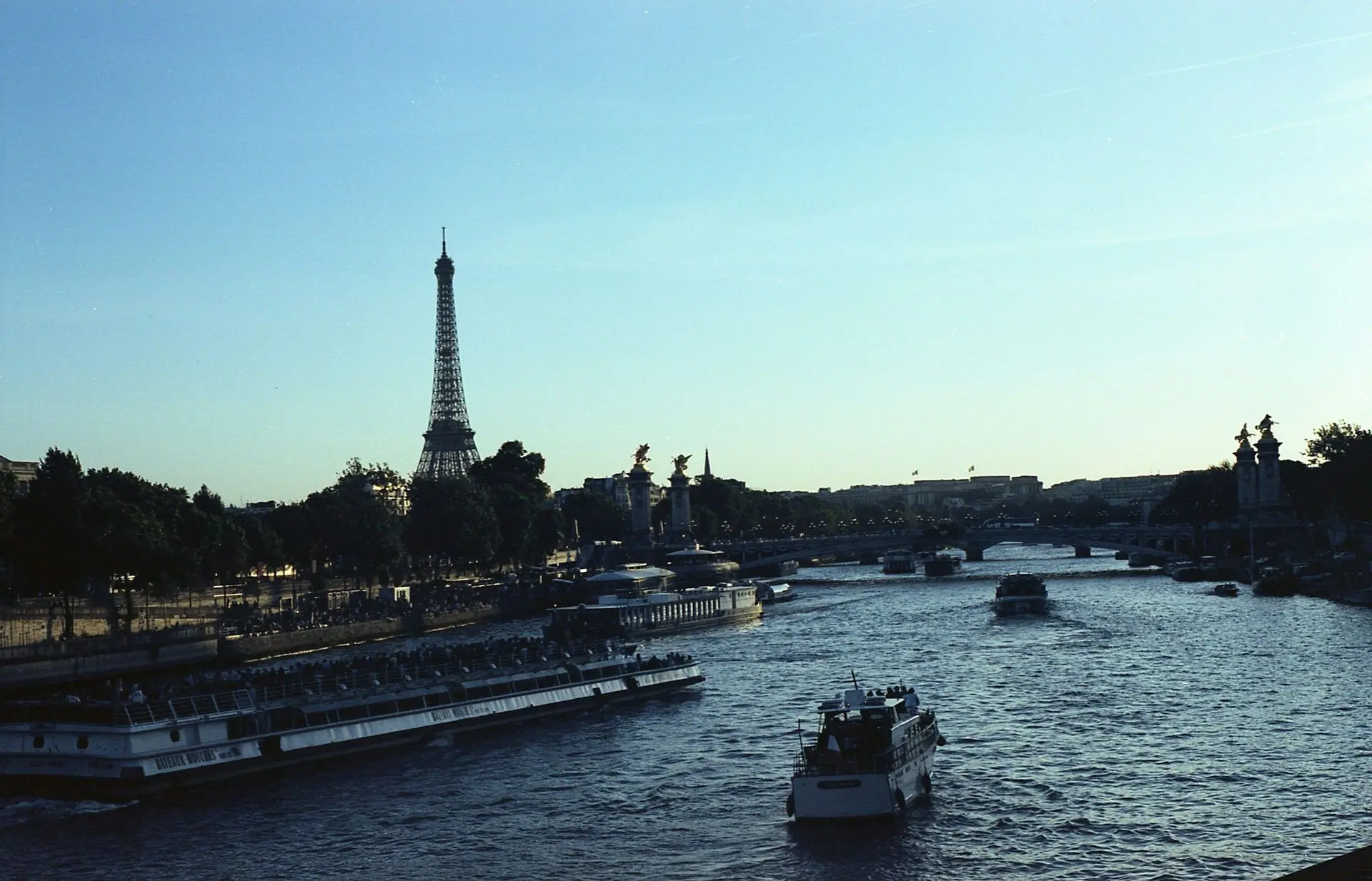 The Eiffel Tower and boats on the Seine seen from across the river