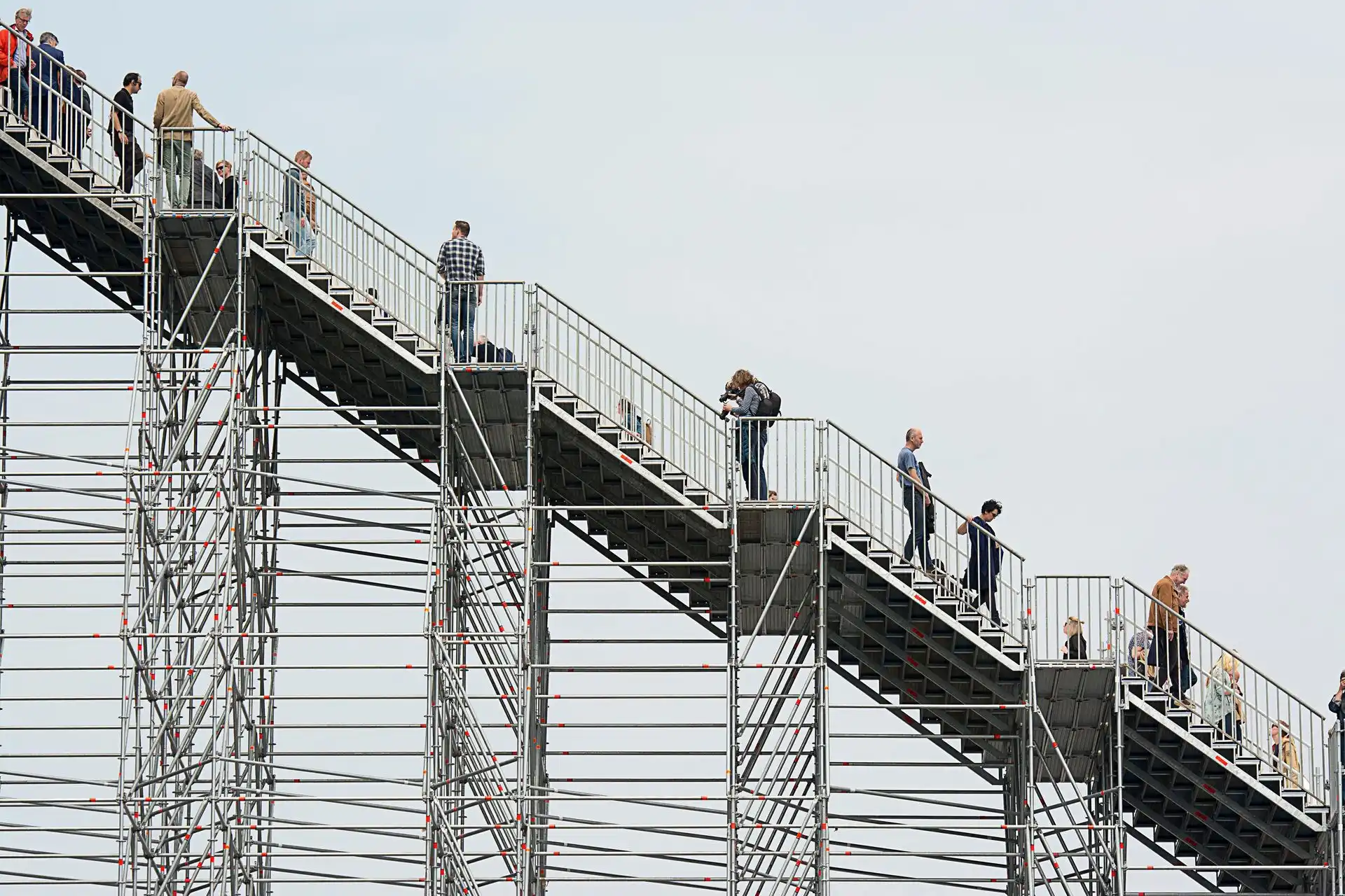 A group of people walking up a large metal stairway structure A group of people walking up a large metal stairway structure