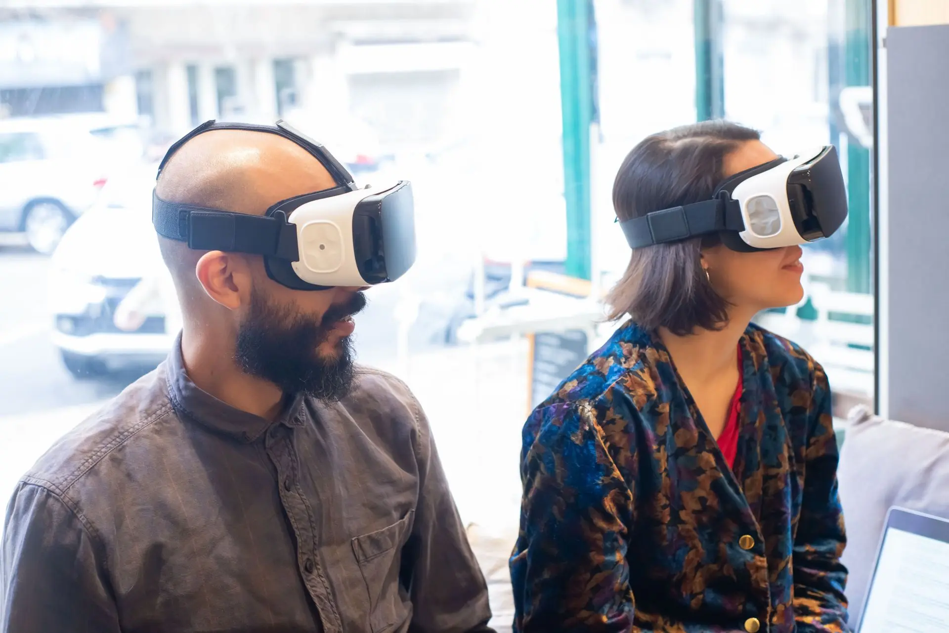 Two adults wearing VR headsets exploring a virtual experience Two adults wearing VR headsets exploring a virtual experience